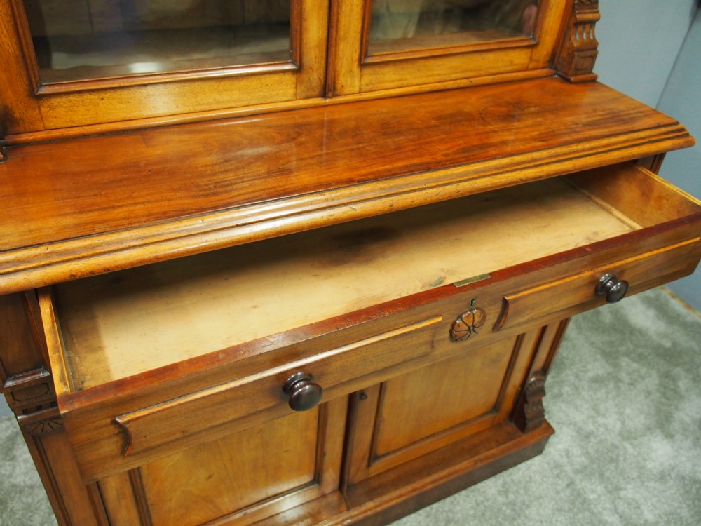 A mid-Victorian mahogany glazed bookcase cabinet with two glass upper doors above a two-door solid cupboard base with carved details. View VII