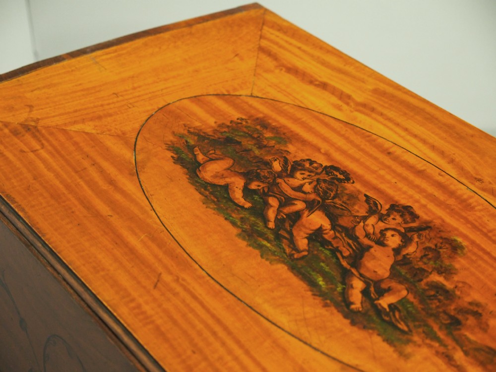 A George III painted satinwood Pembroke table featuring two drop-down leaves, a central oval vignette painting, floral detail, a frieze drawer, and square tapered legs. View V