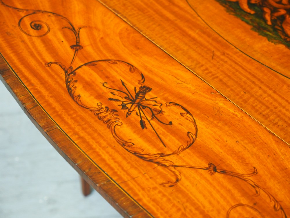 A George III painted satinwood Pembroke table featuring two drop-down leaves, a central oval vignette painting, floral detail, a frieze drawer, and square tapered legs. View X
