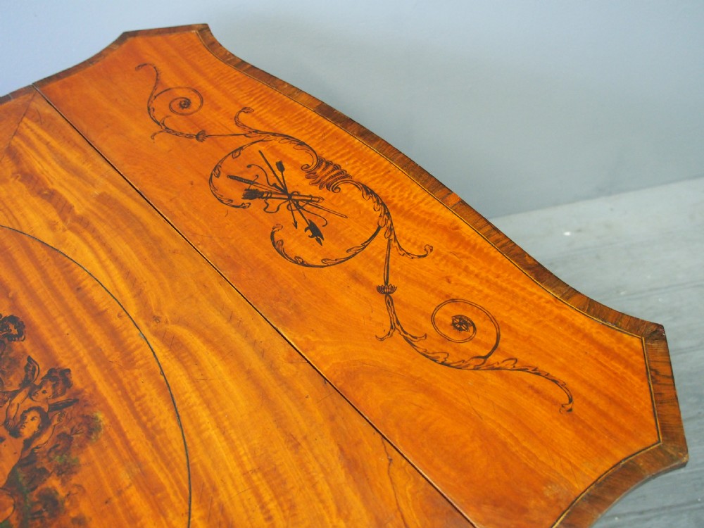 A George III painted satinwood Pembroke table featuring two drop-down leaves, a central oval vignette painting, floral detail, a frieze drawer, and square tapered legs. View XI
