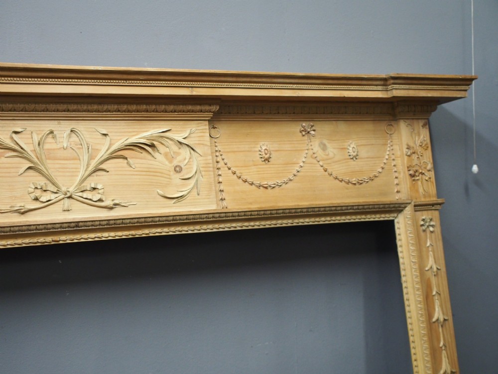 A carved George III pine mantelpiece featuring Neoclassical drapery swags, floral rosettes, and a central foliate scrollwork tablet. View III