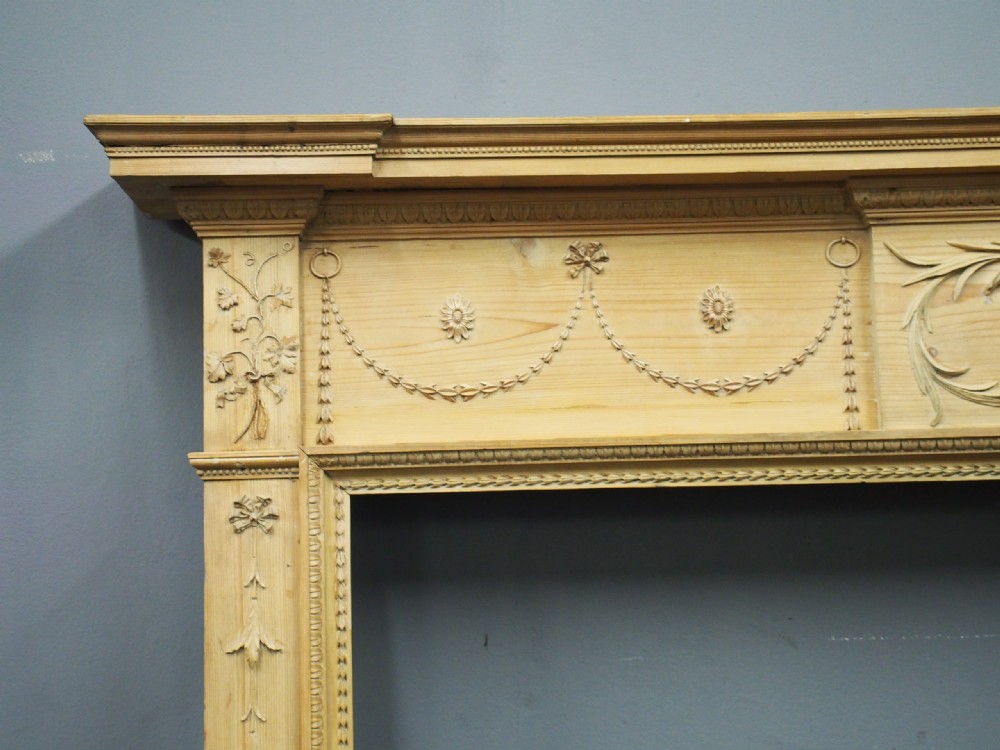 A carved George III pine mantelpiece featuring Neoclassical drapery swags, floral rosettes, and a central foliate scrollwork tablet. View IV
