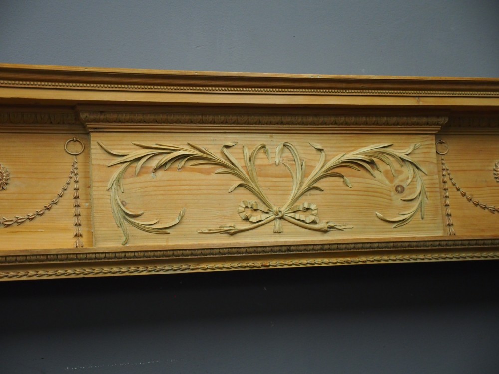 A carved George III pine mantelpiece featuring Neoclassical drapery swags, floral rosettes, and a central foliate scrollwork tablet. View V