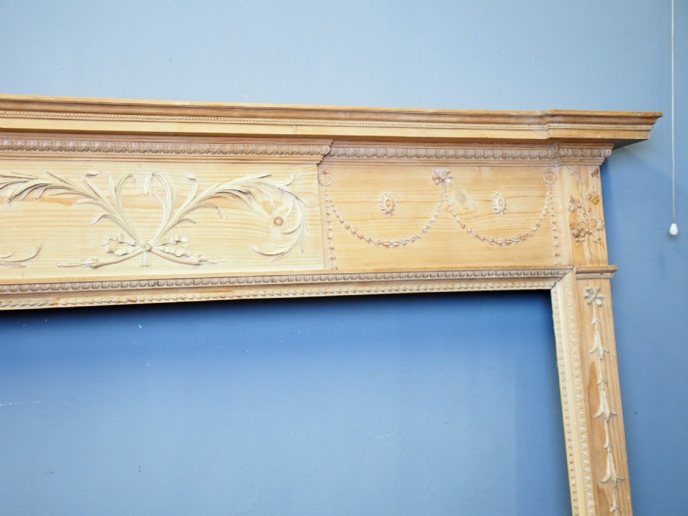 A carved George III pine mantelpiece featuring Neoclassical drapery swags, floral rosettes, and a central foliate scrollwork tablet. View VII