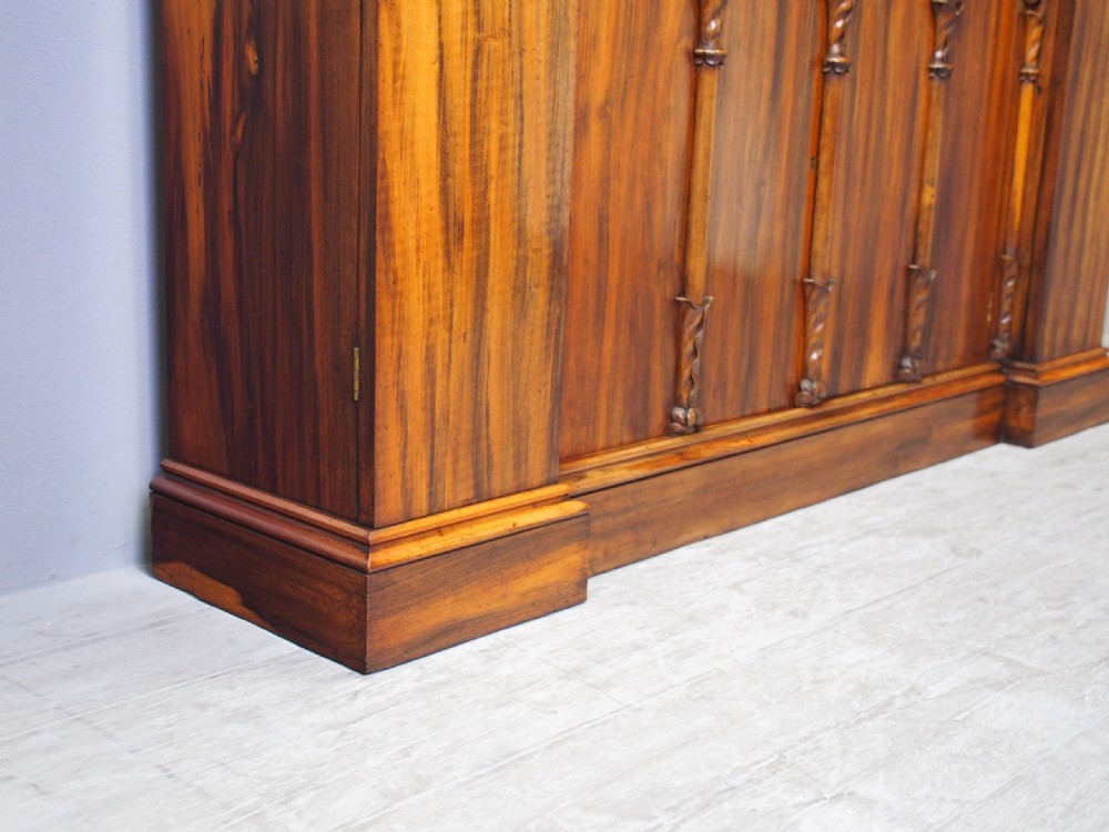 A Regency period goncalo alves wood cabinet featuring two outer pedestal towers and carved leaf motif pilasters along the central panel. View XIV