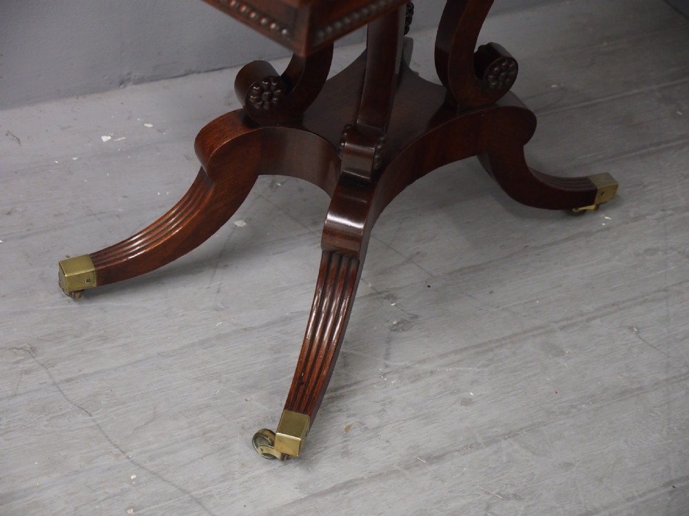 A Regency mahogany fold-over tea table featuring bead moulding along the frieze, set on scrolled supports and reeded splayed legs with brass castors. View X