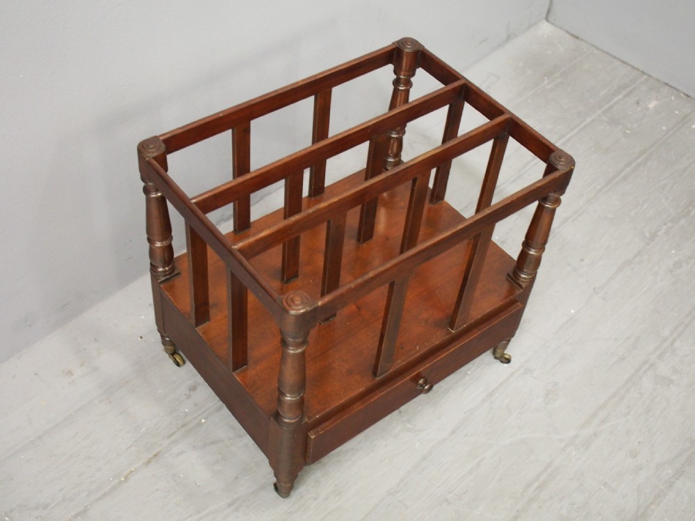 A George III mahogany Canterbury featuring vertical slatted partitions, turned corner posts, a lower drawer with a turned knob, and brass castors. View IV