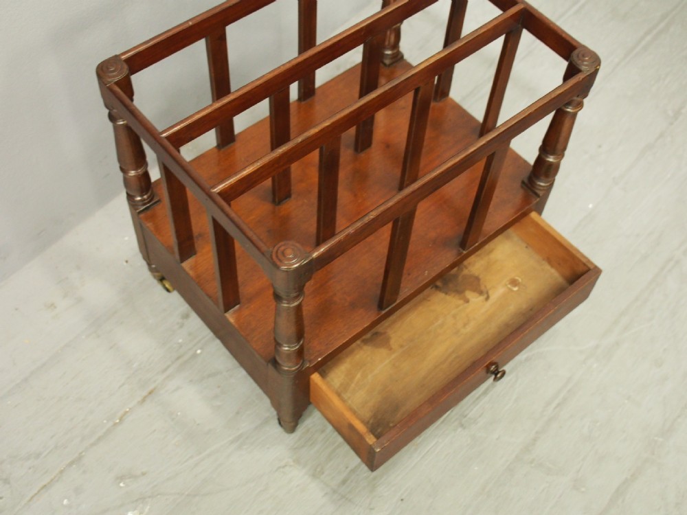 A George III mahogany Canterbury featuring vertical slatted partitions, turned corner posts, a lower drawer with a turned knob, and brass castors. View V
