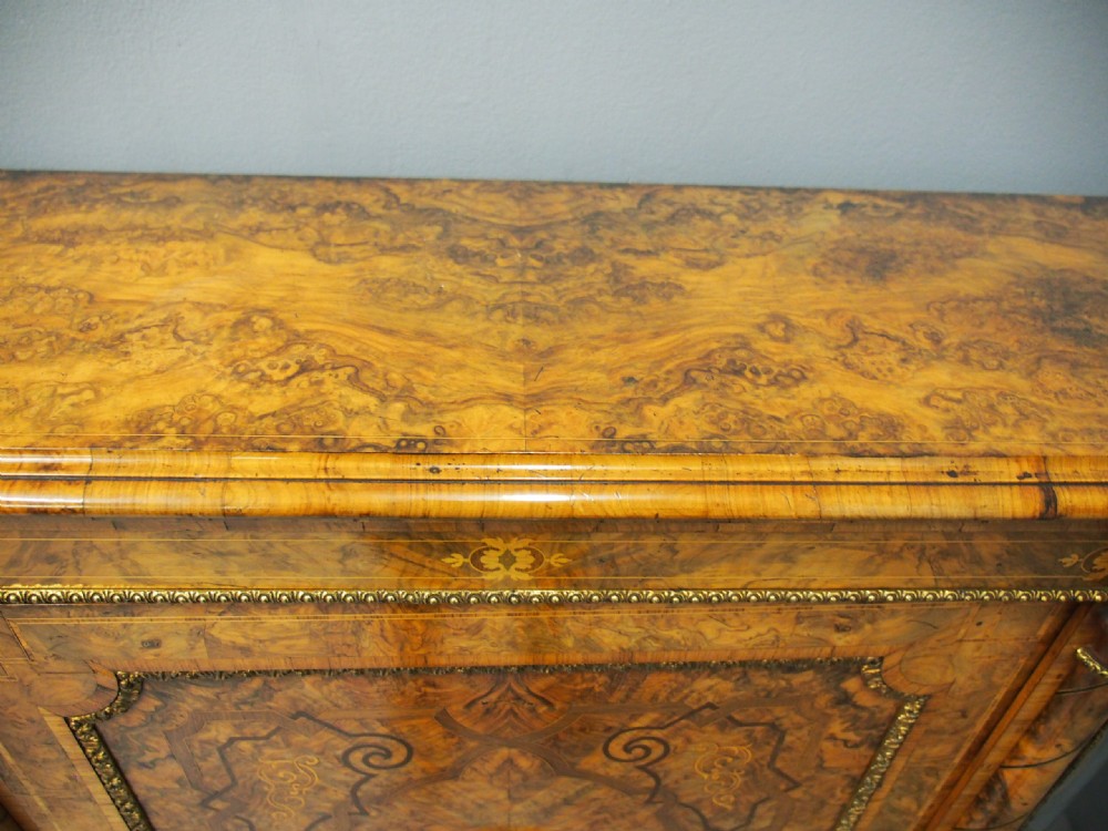 Victorian burr walnut credenza featuring a central door with marquetry inlay and a porcelain medallion, flanked by two curved glazed side cabinets with gilt mounts. View VIII