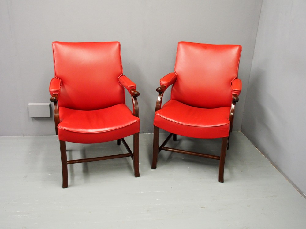 A pair of red leather armchairs with dark mahogany frames and padded armrests. View III