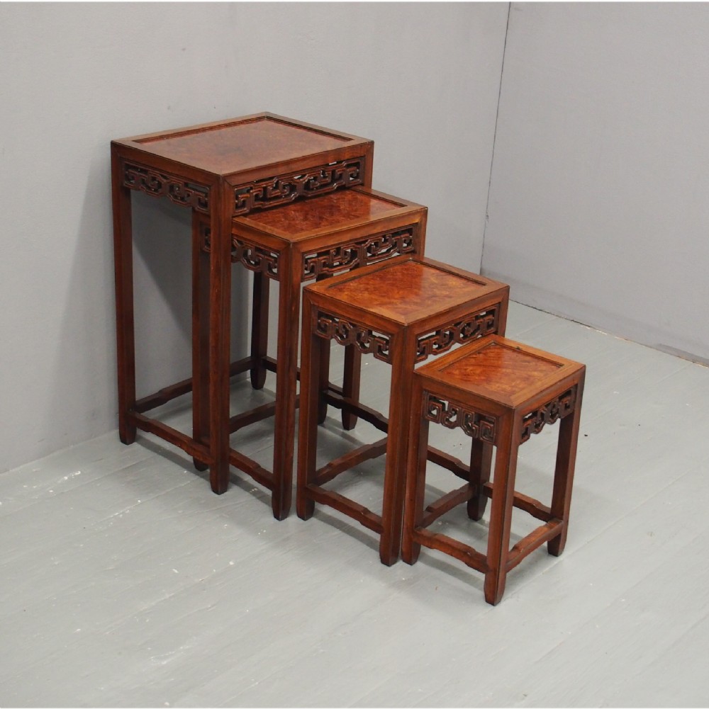 A set of four graduated Chinese Hongmu tables featuring figured burrwood inset tops and carved openwork fretwork aprons.