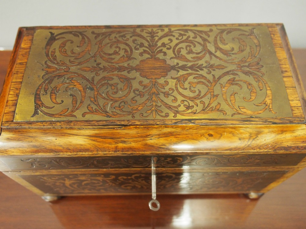 An antique dark rosewood tea caddy featuring intricate brass scrollwork inlay, side wooden ring handles, and turned bun feet. View VIII