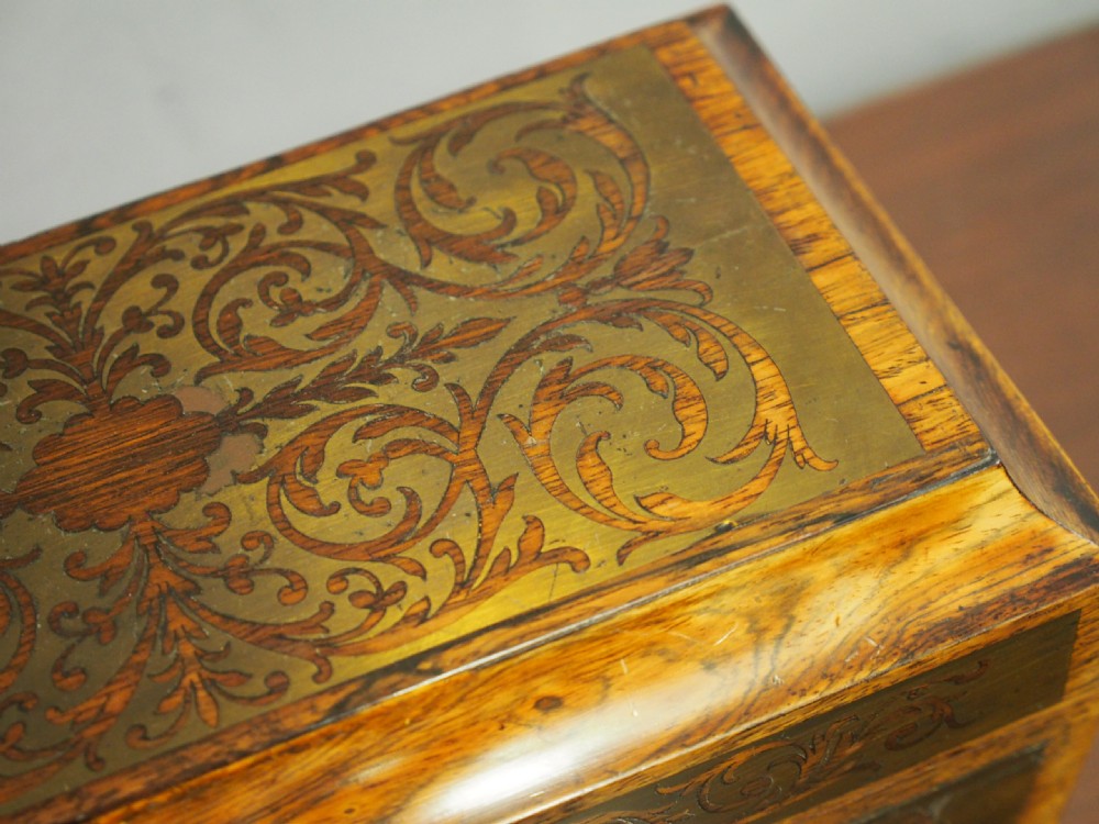An antique dark rosewood tea caddy featuring intricate brass scrollwork inlay, side wooden ring handles, and turned bun feet. View IX