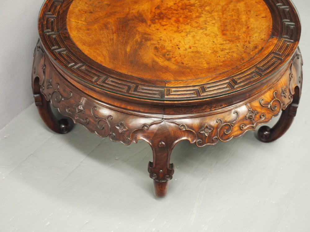 A circular low Chinese hardwood table featuring a glass top over a fretwork border, carved aprons, and curved legs. View VI