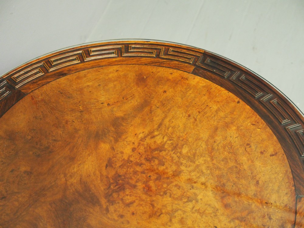 A circular low Chinese hardwood table featuring a glass top over a fretwork border, carved aprons, and curved legs. View IX