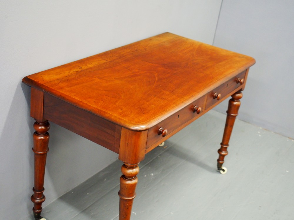 Victorian mahogany side table featuring two frieze drawers with wooden knob handles, turned legs, and white ceramic castors. View III