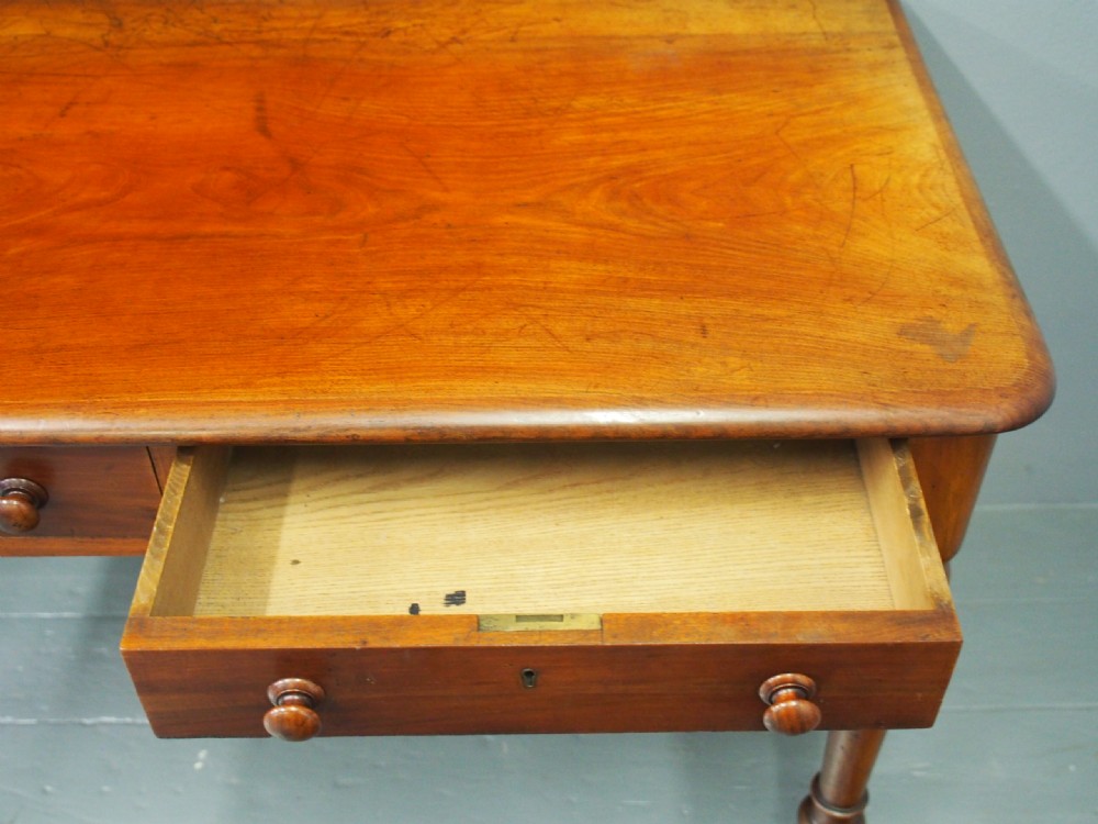 Victorian mahogany side table featuring two frieze drawers with wooden knob handles, turned legs, and white ceramic castors. View VII