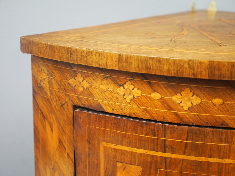 A floor-standing Dutch walnut corner cabinet featuring a curved front door embellished with figurative and floral marquetry inlays resting on carved legs. View VIII