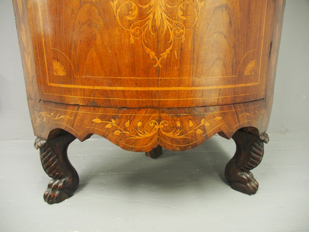 A floor-standing Dutch walnut corner cabinet featuring a curved front door embellished with figurative and floral marquetry inlays resting on carved legs. View XII