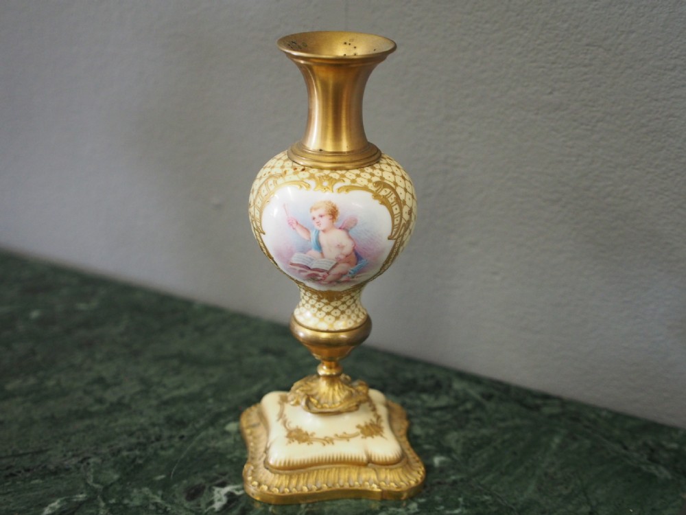 A three-piece French porcelain clock garniture set featuring a central rococo-style clock flanked by two matching vases decorated with hand-painted cherubs and gilded mounts. View VIII