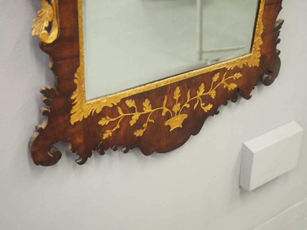 A vertical Chippendale style mahogany wall mirror featuring detailed giltwood foliage carvings along the side margins and top cresting, set against a dark timber frame with fretwork edges. View IV