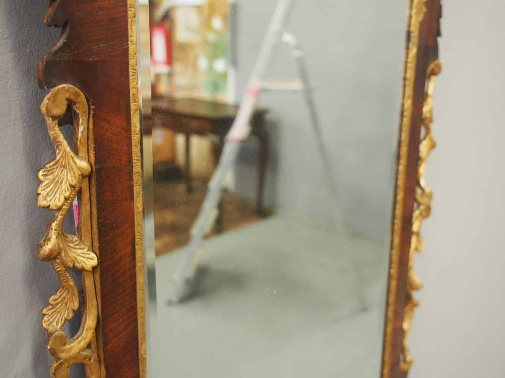 A vertical Chippendale style mahogany wall mirror featuring detailed giltwood foliage carvings along the side margins and top cresting, set against a dark timber frame with fretwork edges. View XIV