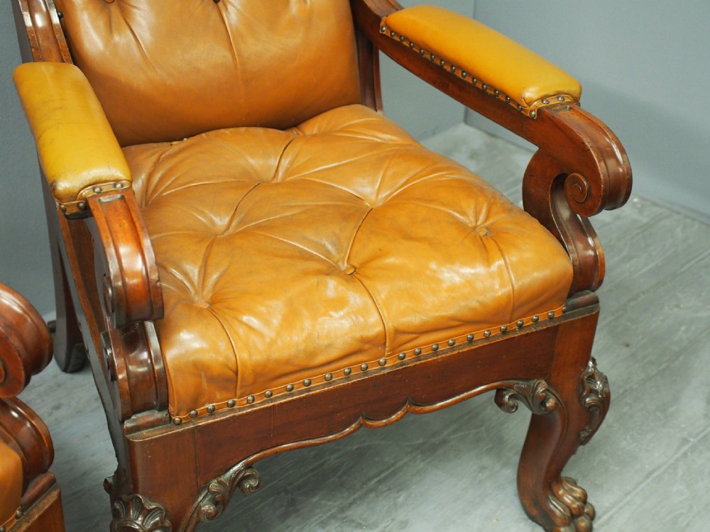 A pair of George IV mahogany armchairs upholstered in button-backed tan leather with carved cabriole legs and brass studding. View VIII