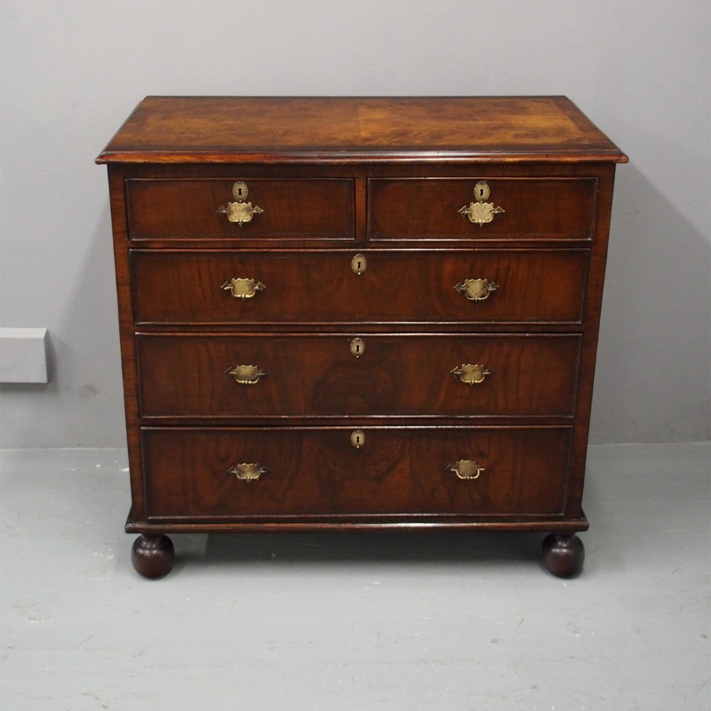 An 18th-century style George III walnut chest of drawers featuring two short over three long drawers with brass handles and escutcheons, set on turned ball feet.