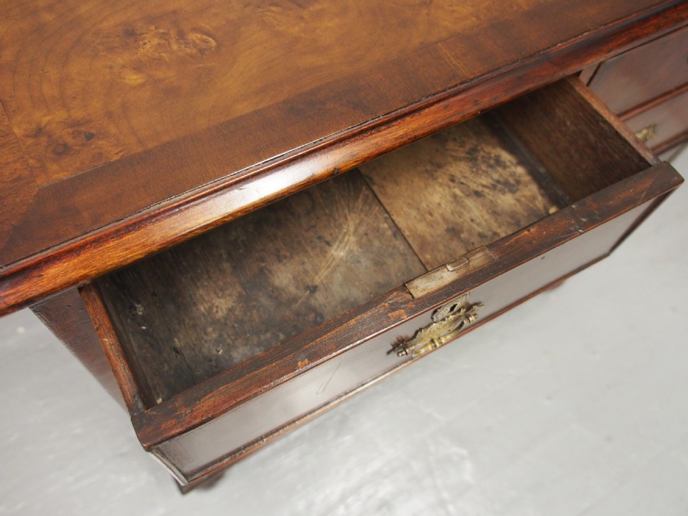 An 18th-century style George III walnut chest of drawers featuring two short over three long drawers with brass handles and escutcheons, set on turned ball feet. View IV