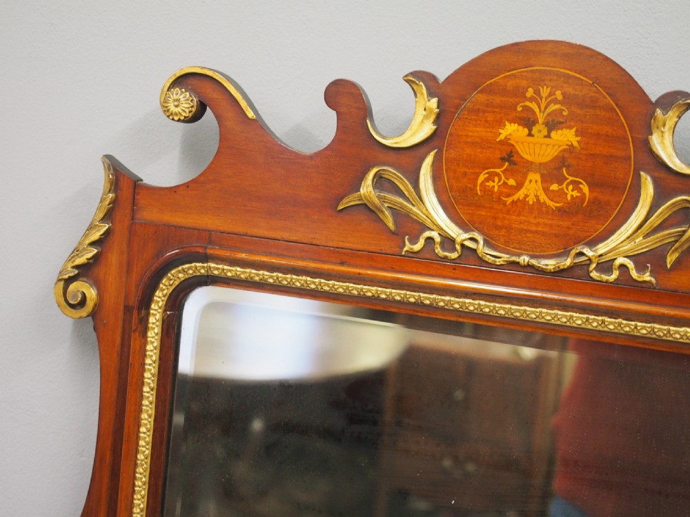 A rectangular George II style wall mirror set in a carved mahogany fretwork frame with gilded accents and a central urn inlay. View V