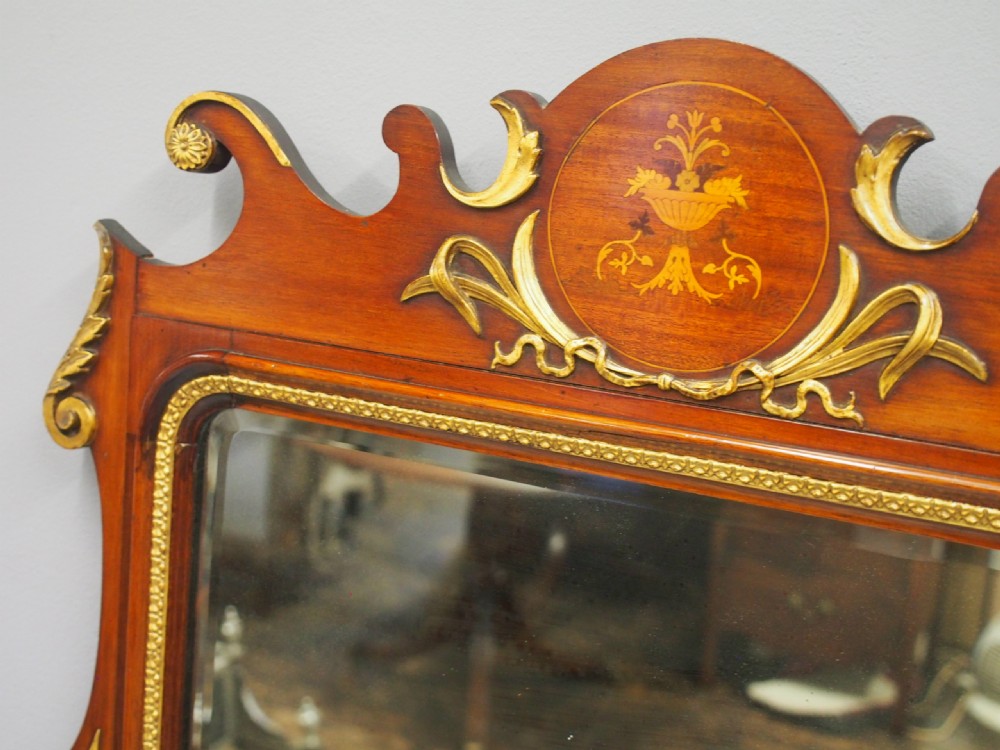A rectangular George II style wall mirror set in a carved mahogany fretwork frame with gilded accents and a central urn inlay. View X