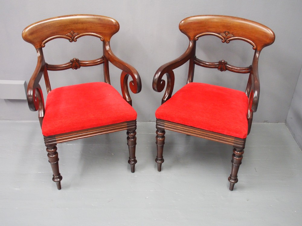 A pair of Victorian mahogany armchairs featuring carved top rails, curved scroll arms, turned front legs, and bright red fabric seat cushions. View IV