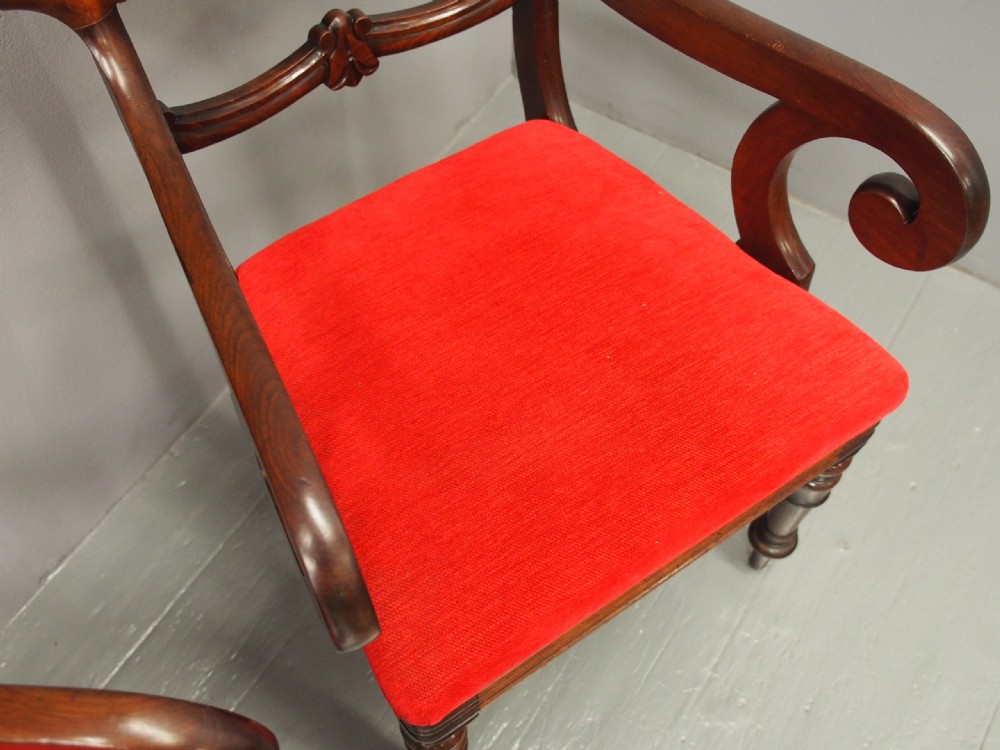 A pair of Victorian mahogany armchairs featuring carved top rails, curved scroll arms, turned front legs, and bright red fabric seat cushions. View VII