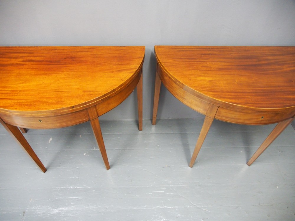 A matching pair of George III demilune mahogany fold-over tea tables with string inlay friezes and square tapered legs. View III