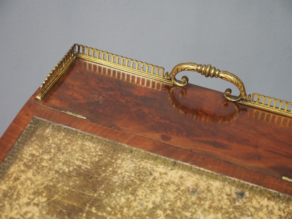 A George IV mahogany Davenport desk with a sloped gold-tooled leather top, upper brass gallery, open side shelving, and brass castors. View IV