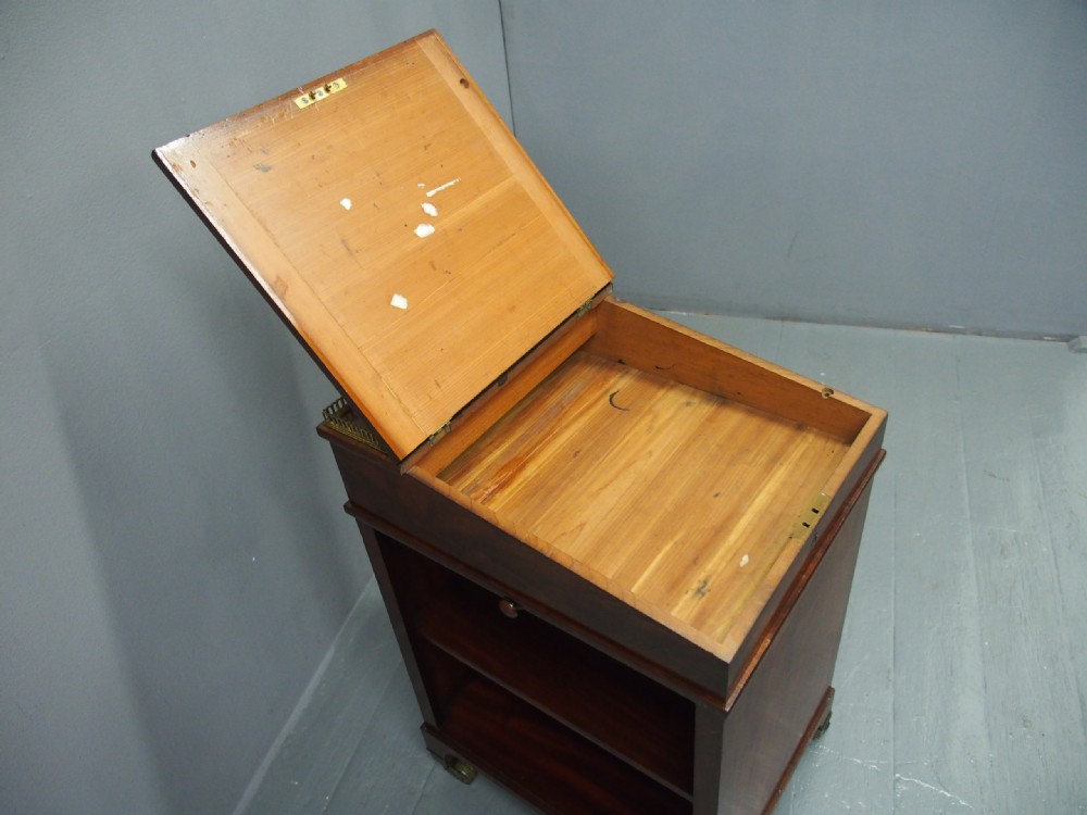 A George IV mahogany Davenport desk with a sloped gold-tooled leather top, upper brass gallery, open side shelving, and brass castors. View VI