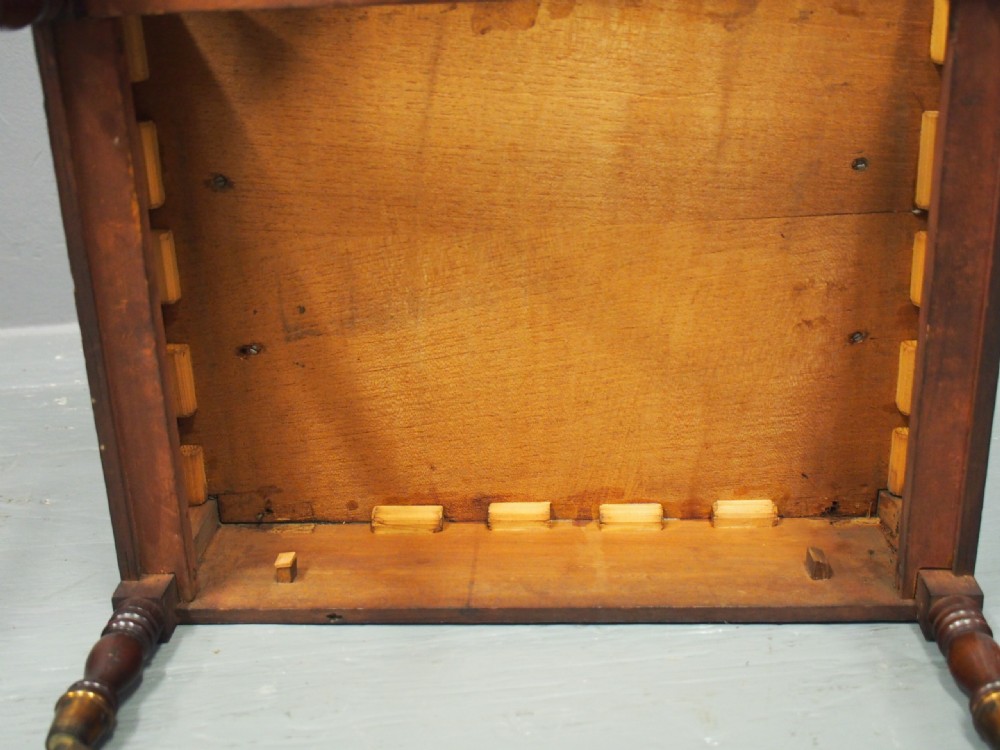 A George IV mahogany Canterbury featuring carved circular dividers, turned corner posts, a single base drawer with two wooden turned knobs, and legs set on brass castors. View XI