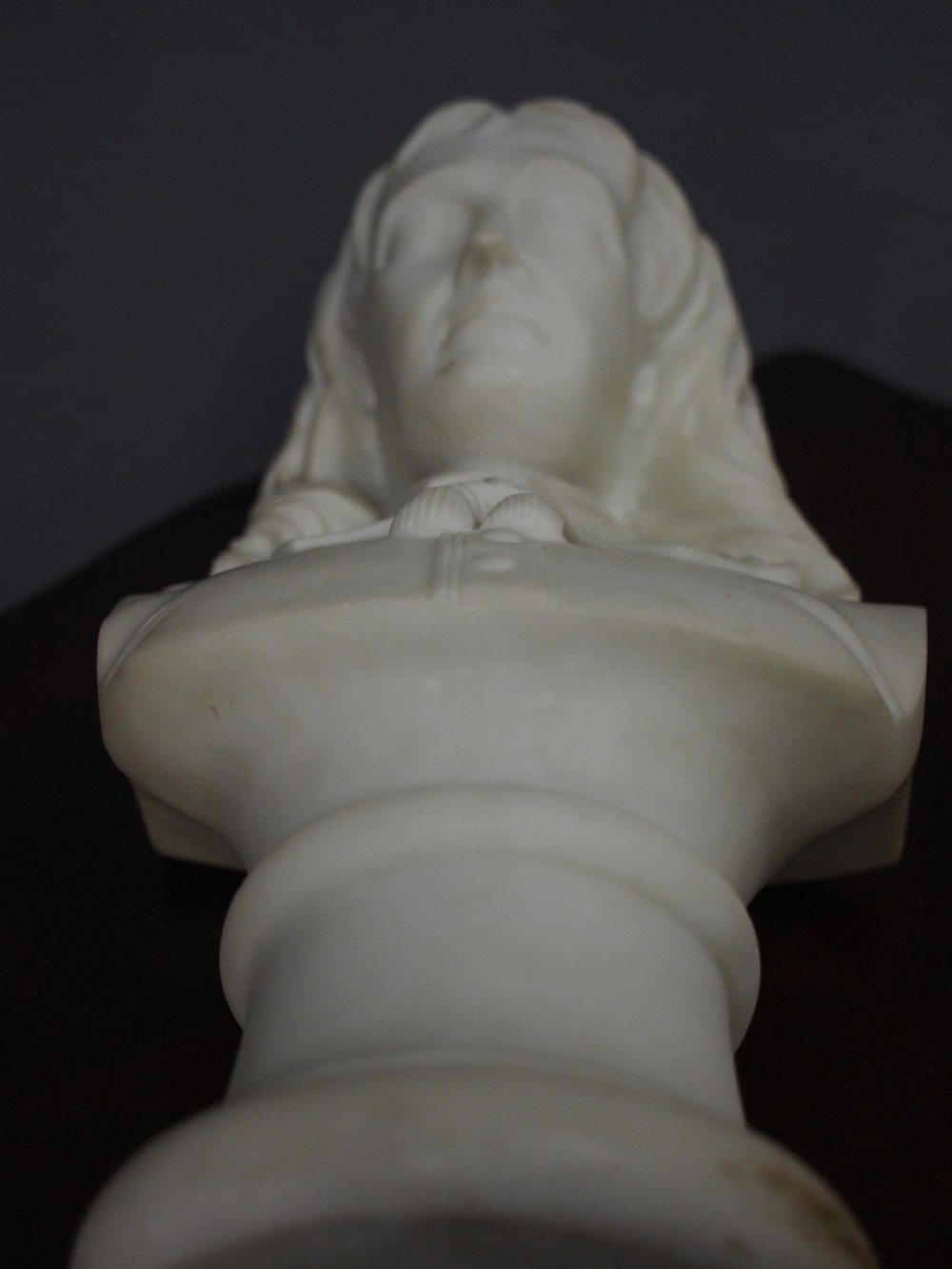 A white marble carved portrait bust depicting a gentleman with long flowing hair and period attire mounted on a round socle base. View VIII