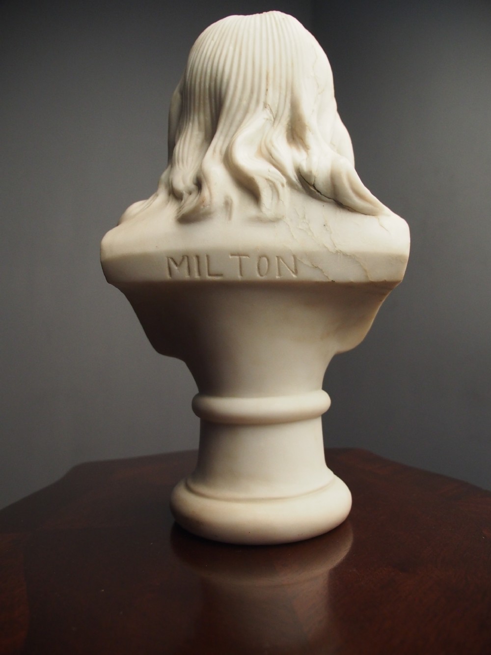 A white marble carved portrait bust depicting a gentleman with long flowing hair and period attire mounted on a round socle base. View XIII
