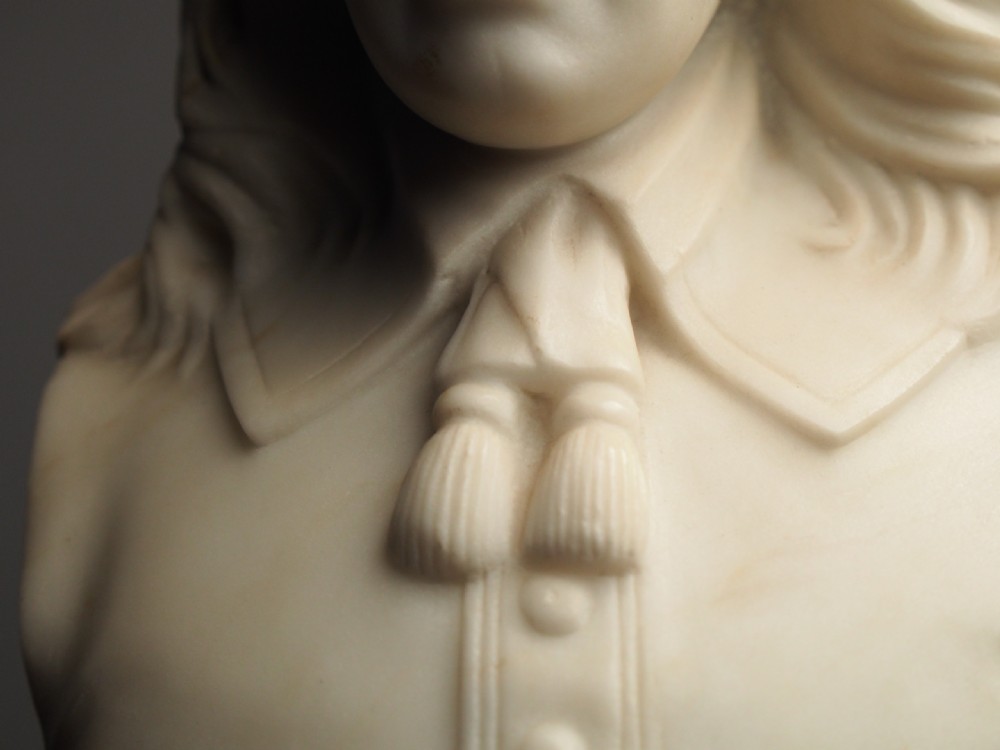A white marble carved portrait bust depicting a gentleman with long flowing hair and period attire mounted on a round socle base. View XV
