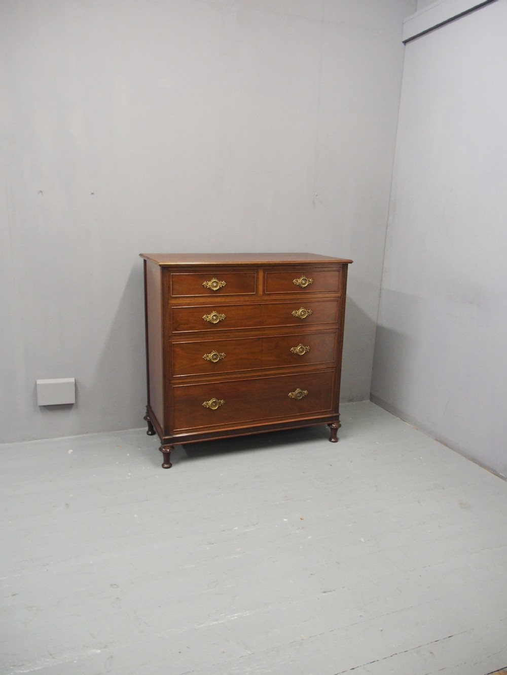 A mahogany chest of drawers in a two short over three long configuration with reeded side columns and cast brass handles. View II