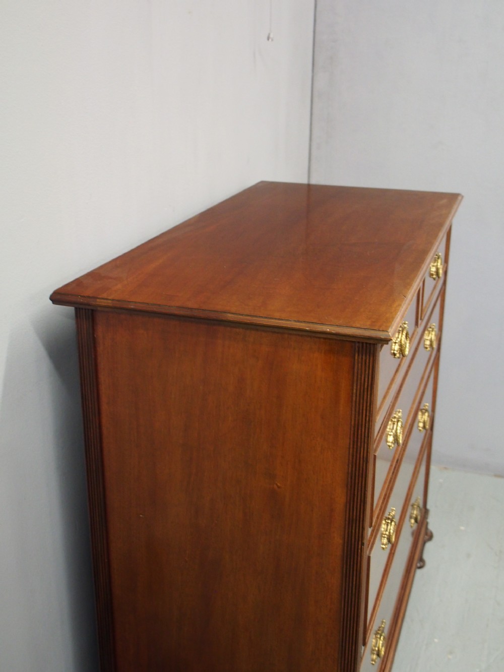 A mahogany chest of drawers in a two short over three long configuration with reeded side columns and cast brass handles. View III