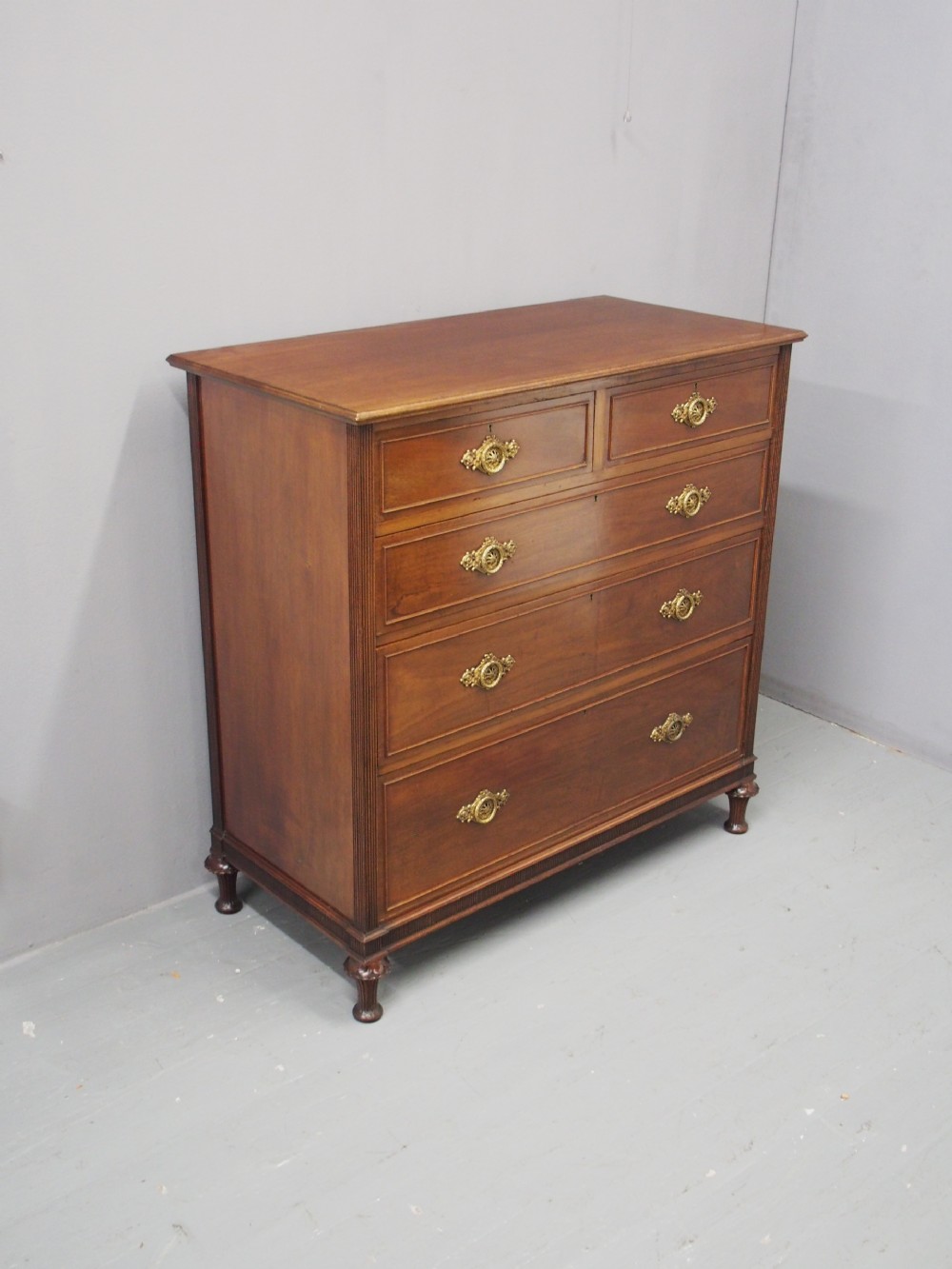A mahogany chest of drawers in a two short over three long configuration with reeded side columns and cast brass handles. View IV