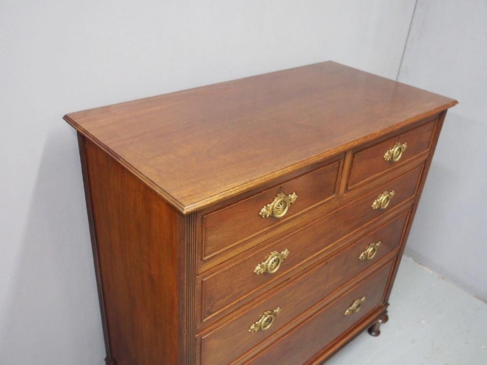 A mahogany chest of drawers in a two short over three long configuration with reeded side columns and cast brass handles. View V