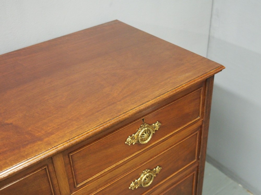 A mahogany chest of drawers in a two short over three long configuration with reeded side columns and cast brass handles. View VIII