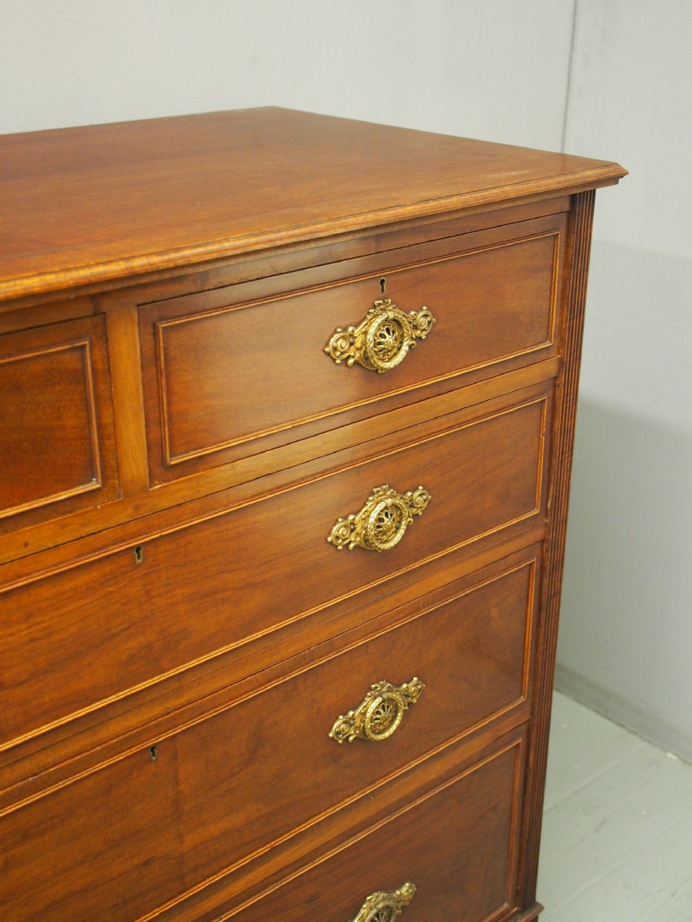 A mahogany chest of drawers in a two short over three long configuration with reeded side columns and cast brass handles. View IX