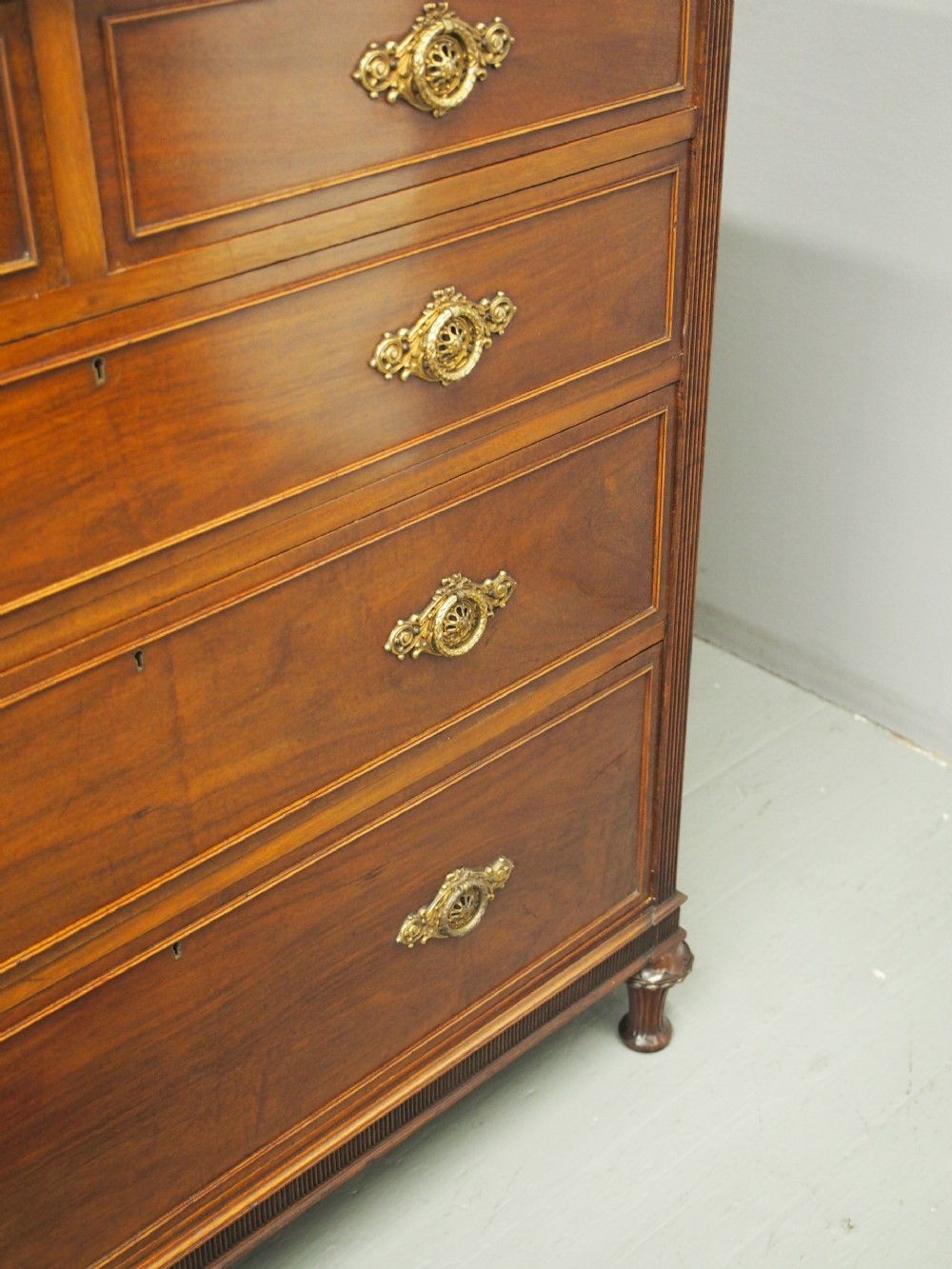 A mahogany chest of drawers in a two short over three long configuration with reeded side columns and cast brass handles. View X