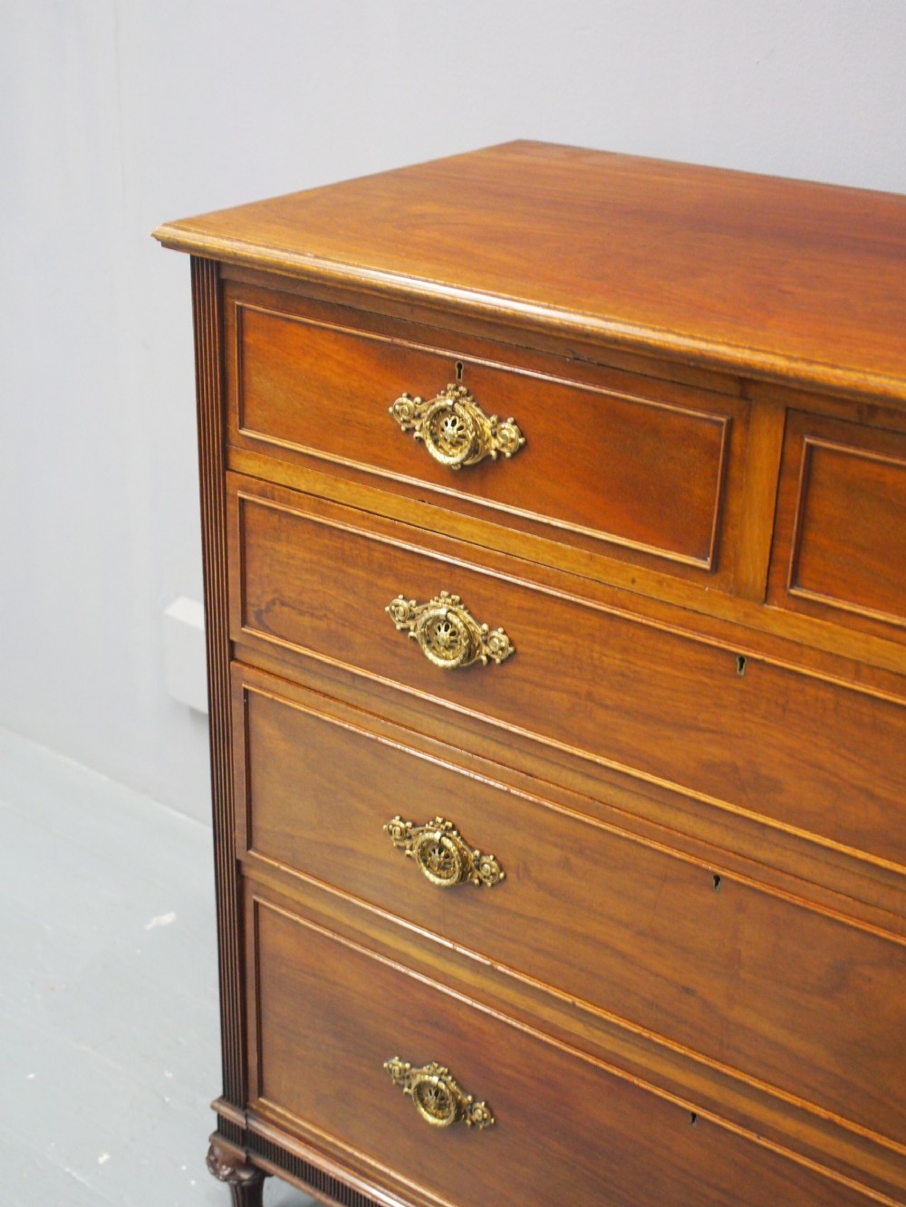 A mahogany chest of drawers in a two short over three long configuration with reeded side columns and cast brass handles. View XII