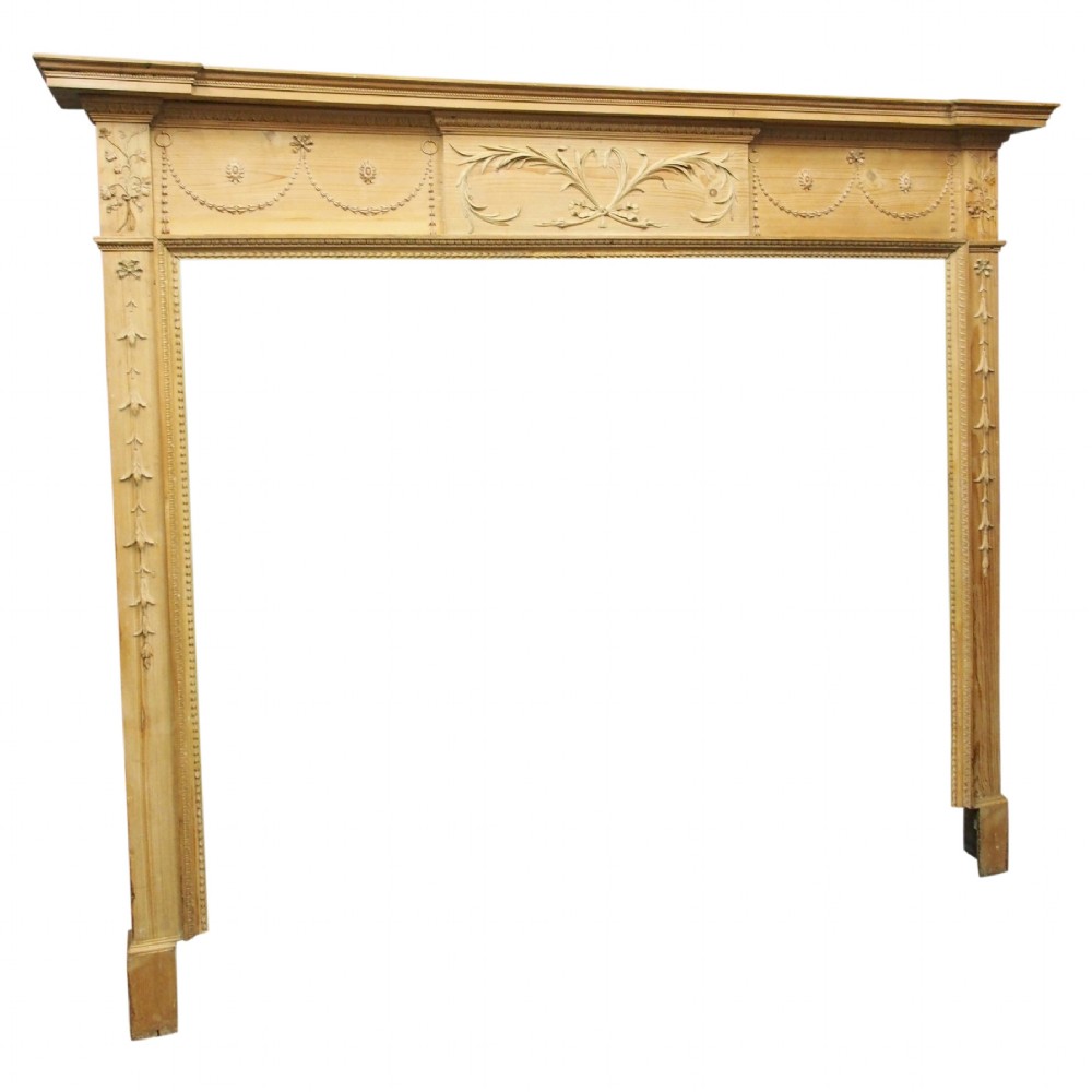 A carved George III pine mantelpiece featuring Neoclassical drapery swags, floral rosettes, and a central foliate scrollwork tablet.