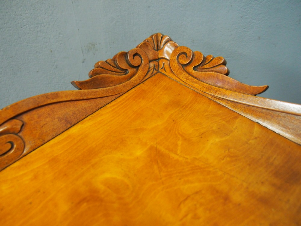 A Victorian satinwood work table featuring a carved top gallery, single drawer, pleated green silk work well, and carved trestle legs. View III